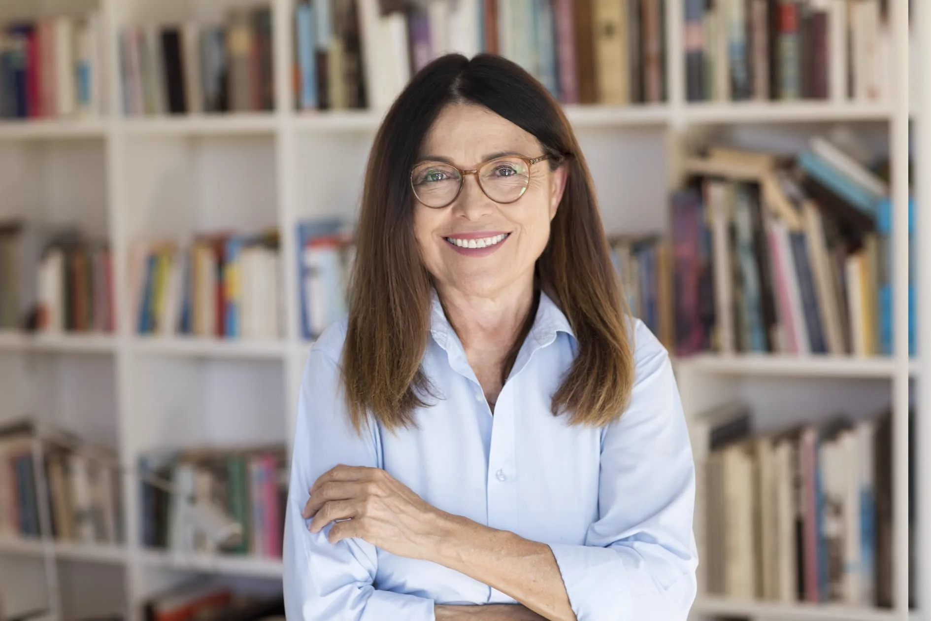 Maria Staub psicanalista em seu consultório, diante de estante de livros
